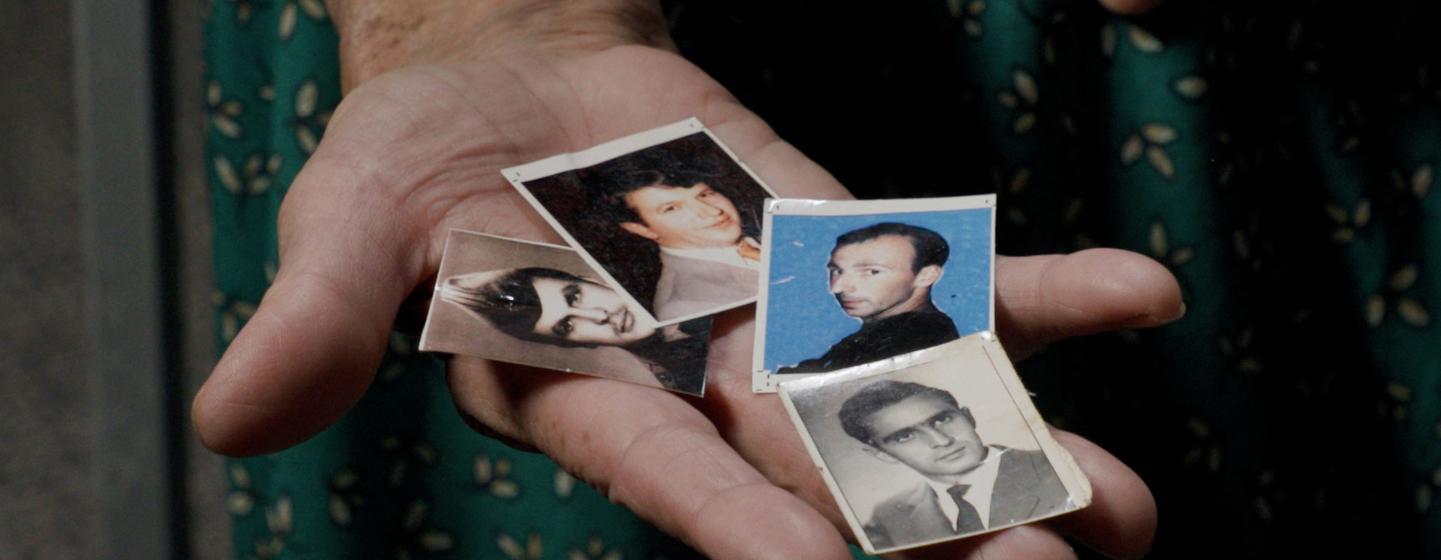 Kada Hoti holds photographs of her son, husband, and two brothers, who were lost in the Srebrenica genocide.