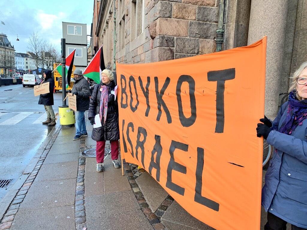 Activists in Denmark hold Palestinian flags banners opposing their governments contracts with Israeli arms firm, Elbit Systems, February 2, 2023 (Photo via Twitter/Pal_action)