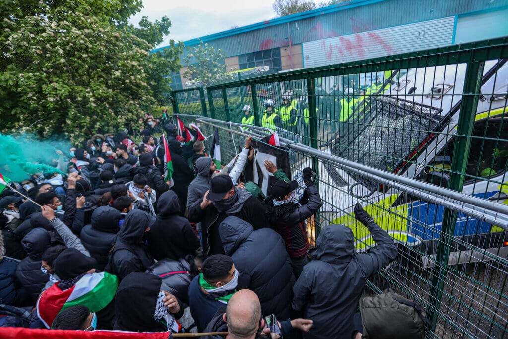 A crowd of activists chant slogans and hold Palestinian flags outside an Elbit UAV weapons factory in Leicester, England to support Palestine Action activists who occupied the building for six consecutive days in May 2021. (Photo by Vudi Xhymshiti)
