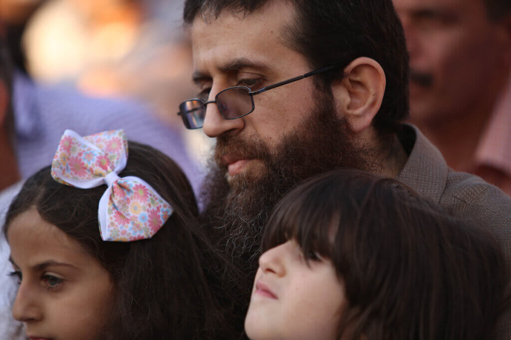 Palestinian martyr Khader Adnan holding two of his children in his lap in 2015.