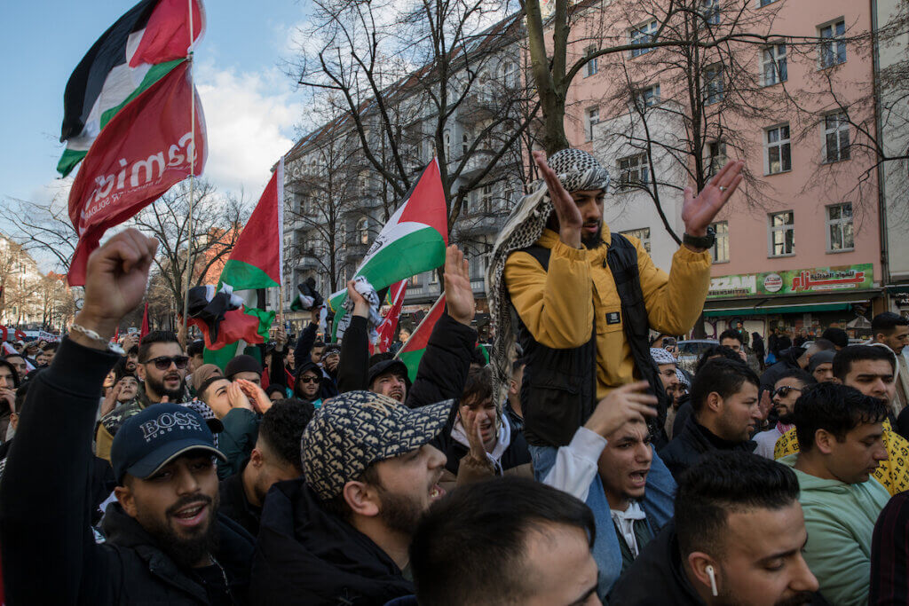 Protesters in Germany carrying Palestinian flags marching through a street in Berlin and chanting.