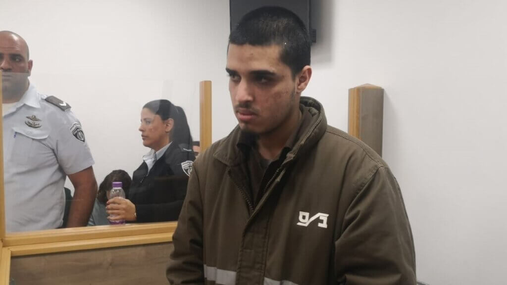 Ahmad Manasra in military court in 2023, dressed in brown Israeli prison or 