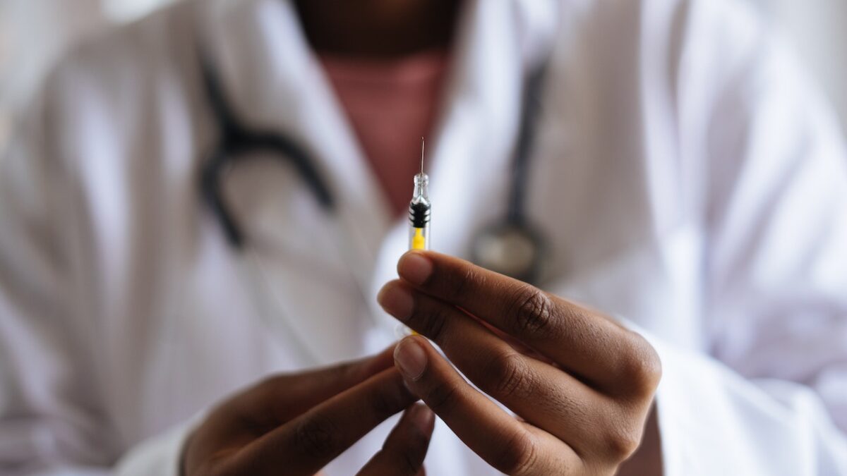 A doctor holds a needle filled with 