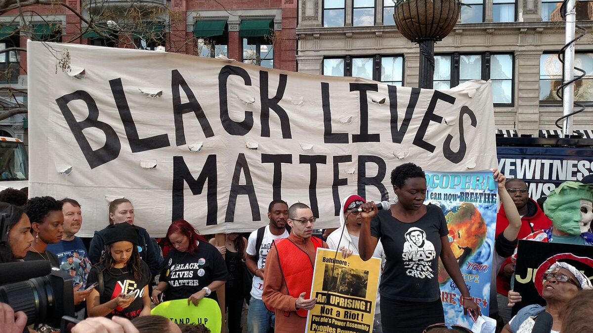 crowd standing in front of giant Black Lives Matter banner